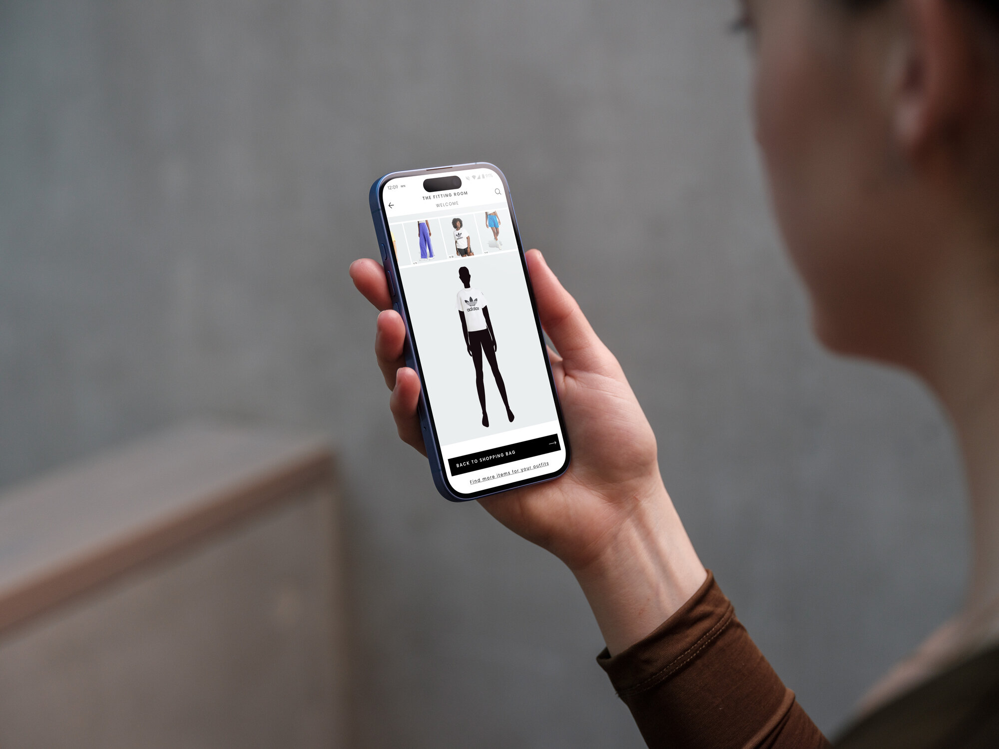 Person holding a phone showing the Adidas Fitting Room prototype outdoors